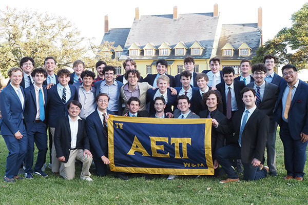 Alpha Epsilon Phi members pose for a group photo behind a flag with their Greek letters.