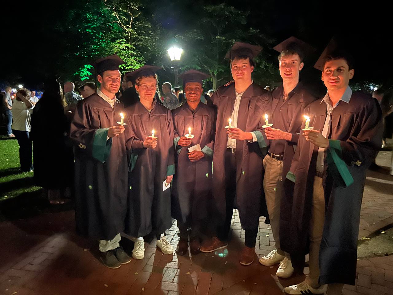 Psi Upsilon brothers hold candles at graduation.