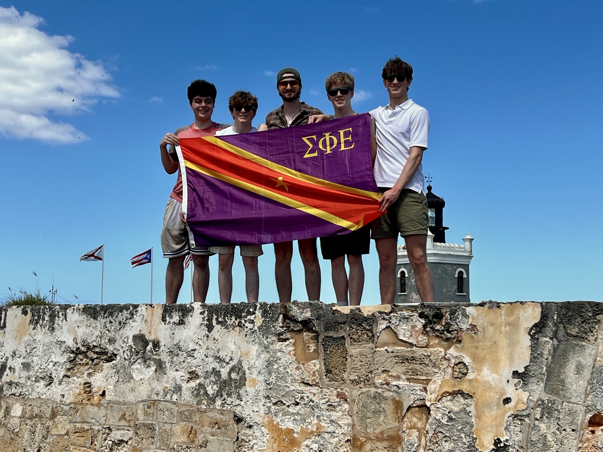 Members of Sigma Phi Epsilon pose on a wall with the flag.