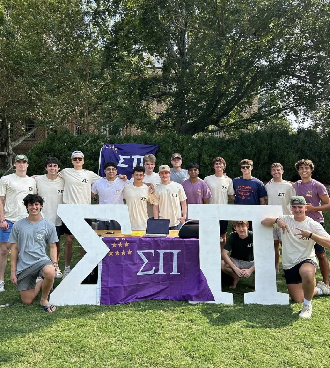 Members of Sigma Pi around a table with their letters and flags.