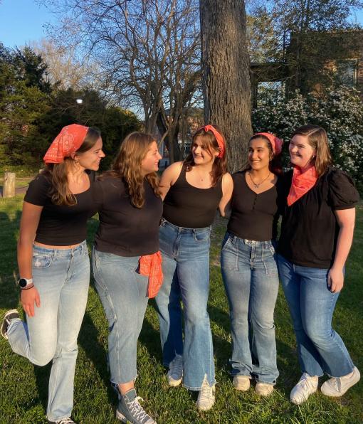 Five smiling people in jeans and black tshirts with red bandanas