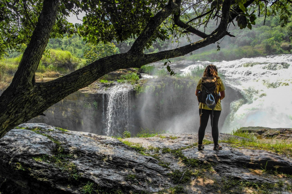 A student stands near a waterfall.