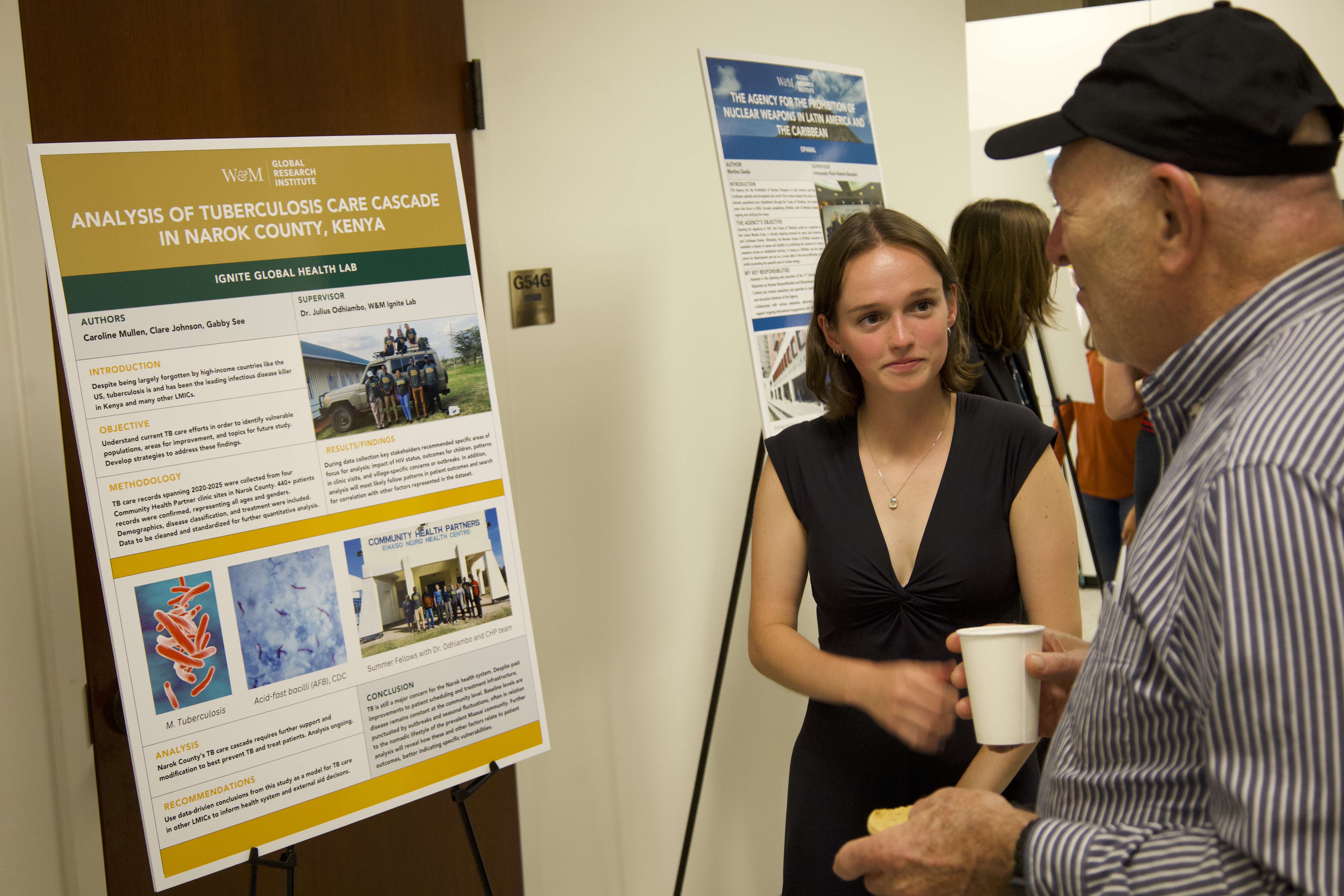 A student shares a poster with their research at an open house. 