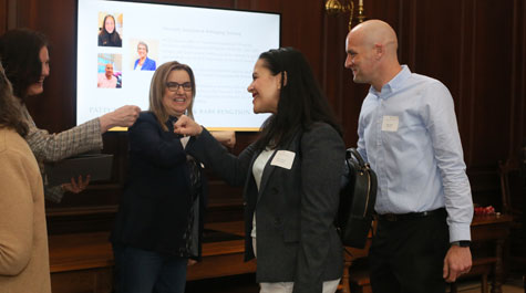 Patty Cox and Nick Artime give president Katherine rowe a fist bump. 
