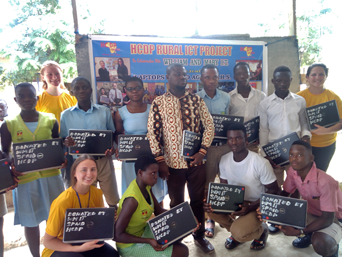 Ghanaian students with their laptops donated from W&M in front of a poster highlighting HDCP's collaboration with W&M.
