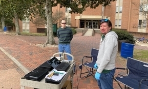 Danny Clouser (left) and Brandon Bell (right) work to distribute loaner laptops to William &amp; Mary employees in front of Morton Hall.