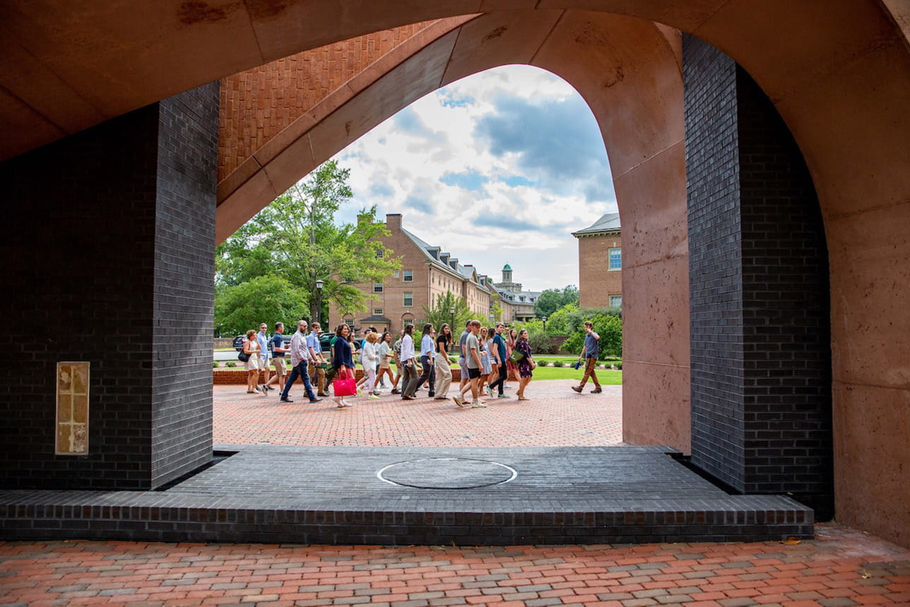 A group of students and their families in a group tour of campus, with William & Mary Memorial to the Enslaved in the foreground
