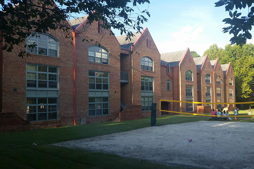 A row of three story brick residences with large windows and a sand volleyball pit