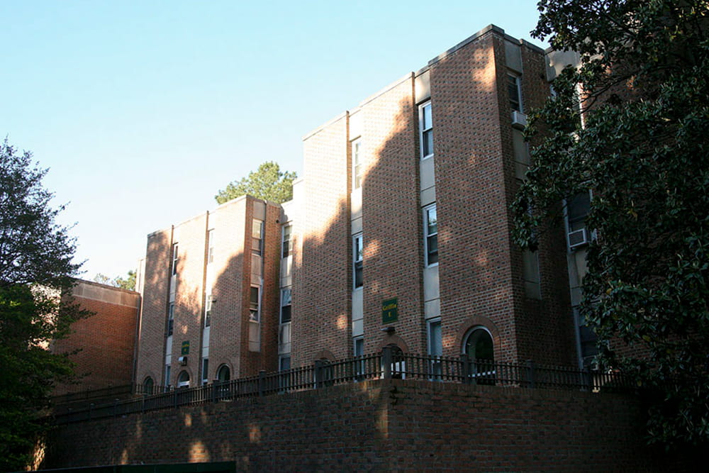 Large brick back porch attached to the brick Griffin Hall, nestled amongst the trees