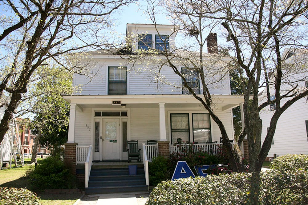An historic house with dormer window, front porch and white siding on a residential street