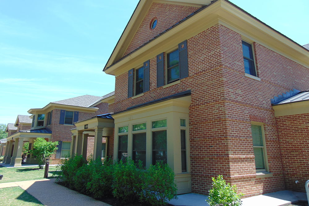 Brick fraternity house in a row with other houses in a grassy area