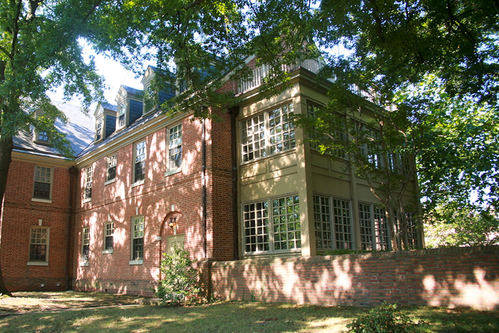 Brick dorm building with a large, windowed space nestled in greenery.