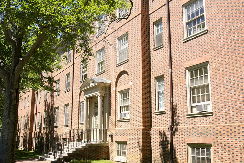 A four story brick building with mature trees nearby