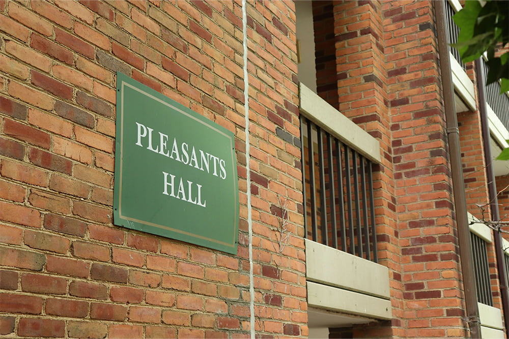 brick building with open breezeways and a sign that reads Pleasants Hall