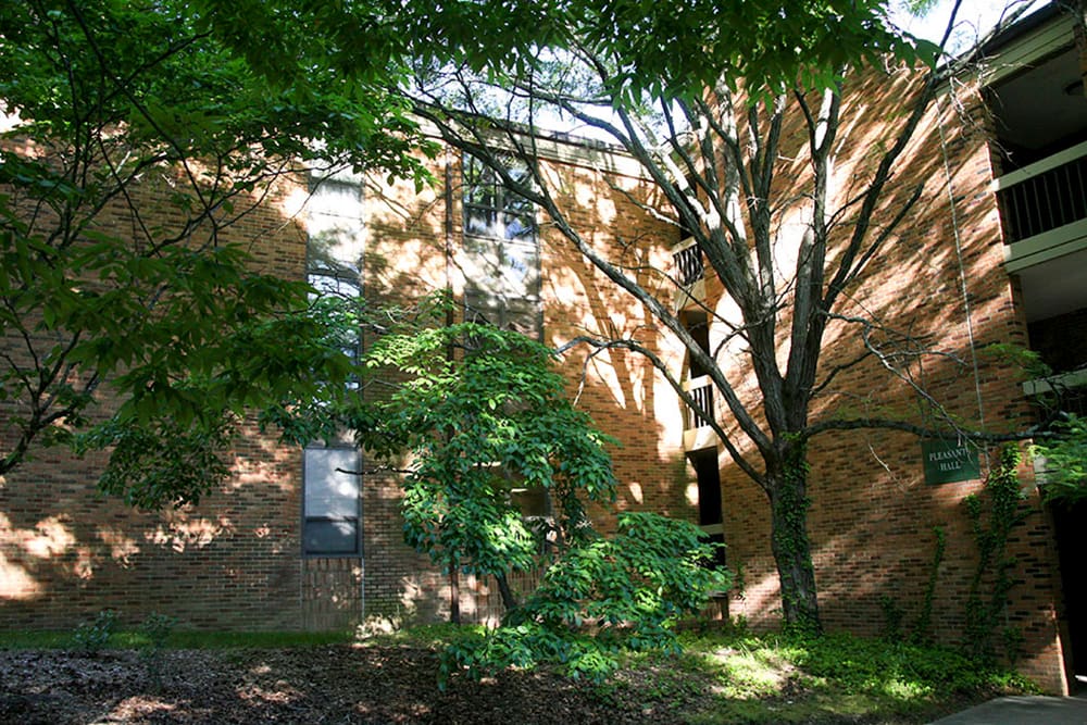 A three story brick building with exposed breezeways nestled in a wooded setting