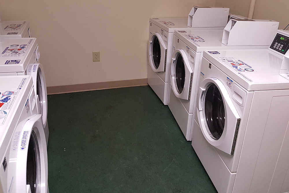 Front loading washer and dryer machines in a dorm laundry room.