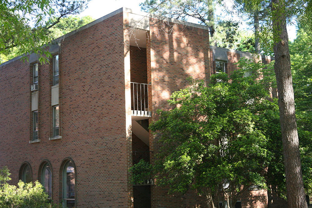A stairwell of a brick, windowed dorm building.