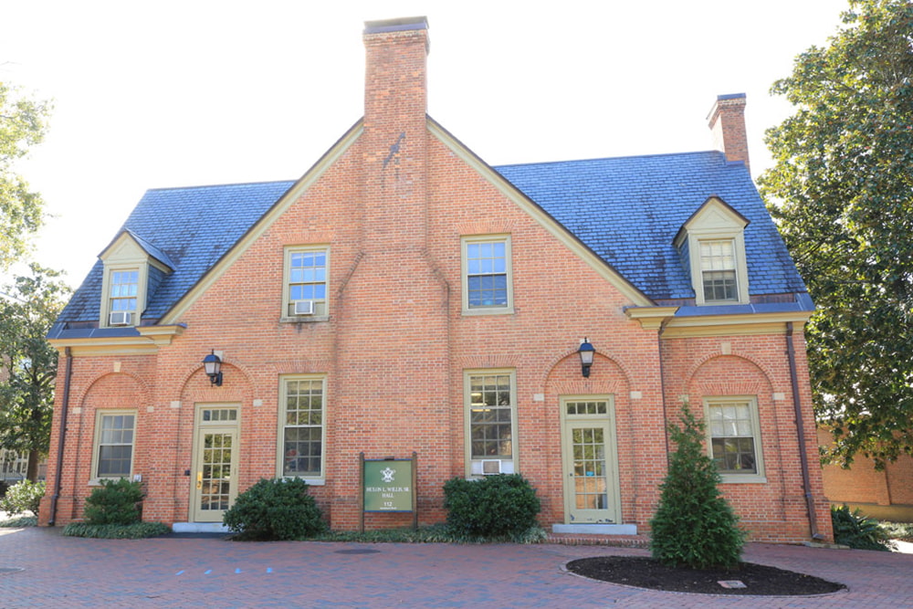 Brick dorm building with two entrances, windows and a patio. 