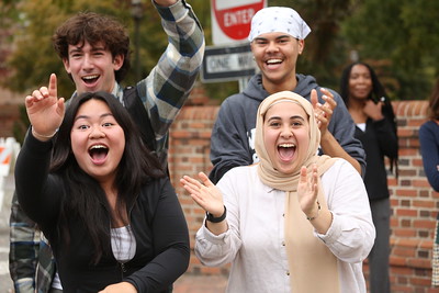 A group of students cheering on campus grounds.