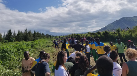 People stand in the countryside with mountains visible in the background
