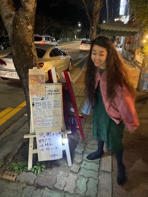 Bottom: Mika outisde a small café. She befriended the owner and his wife, who hosted classical performers every month. They asked Mika to perform a set (singing in Korean and English). The sign is detailing her performance before the owner and his friend (a guitar duo) perform. (Courtesy photo)