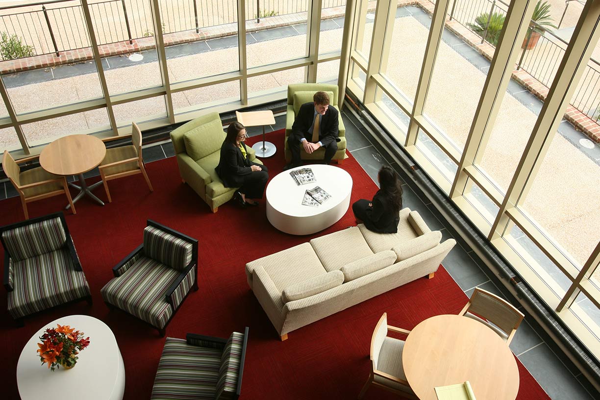 An overhead photo of three people seated and talking to one another.