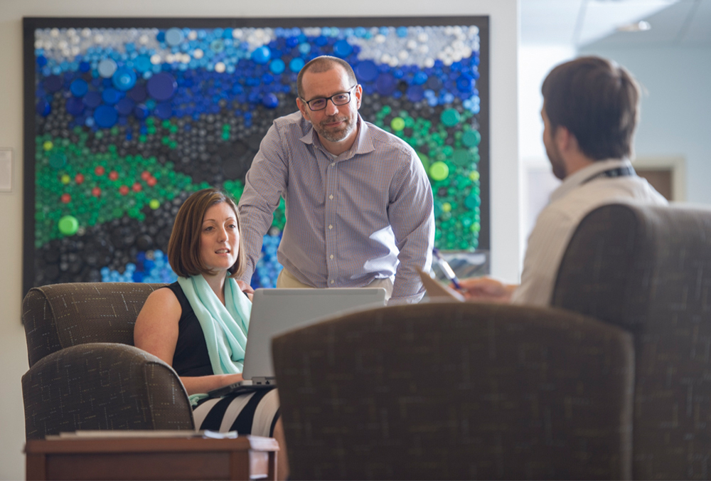 A faculty member chats with two students.