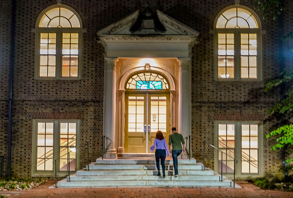 Two people walking up stairs to enter a building.