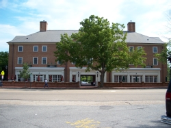 The front of Tribe Square. The building is a long, brick structure with multiple storefronts and a large number of windows above the storefronts/