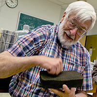 Chemist Robert Orwoll (left) raps his knuckles on a sample regolith-polymer brick