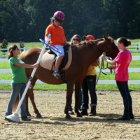 Riding students take a turn around the ring at Dream Catchers at the Cori Sikich Therapeutic Riding Center in Toano