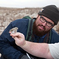 Ellison Orcutt inspects an Ipswich sparrow held by CCB biologist Fletcher Smith 