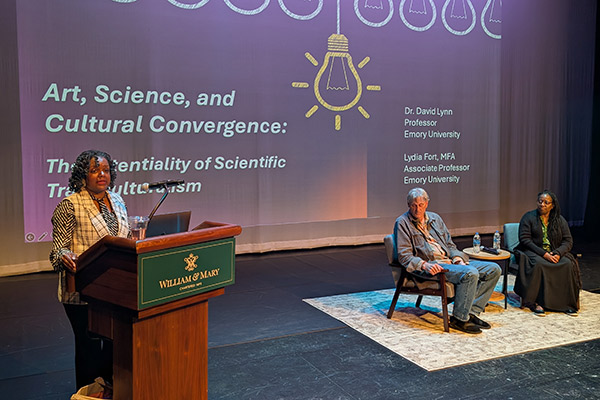 One person at a William & Mary podium and two people seated in conversational chairs on a stage