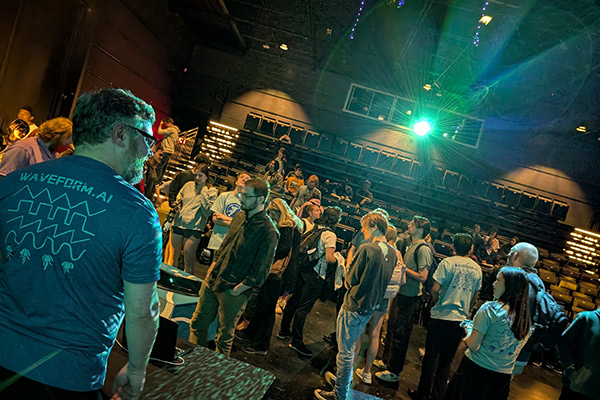 View facing the back of Commonwealth Auditorium with the light of a project shining bright over audience members and Wafeform.AI project members