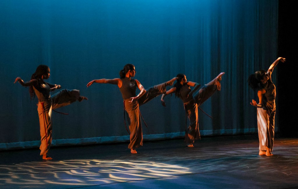 Waves of Wonder dancers performing on stage with a watery blue backdrop and lighting