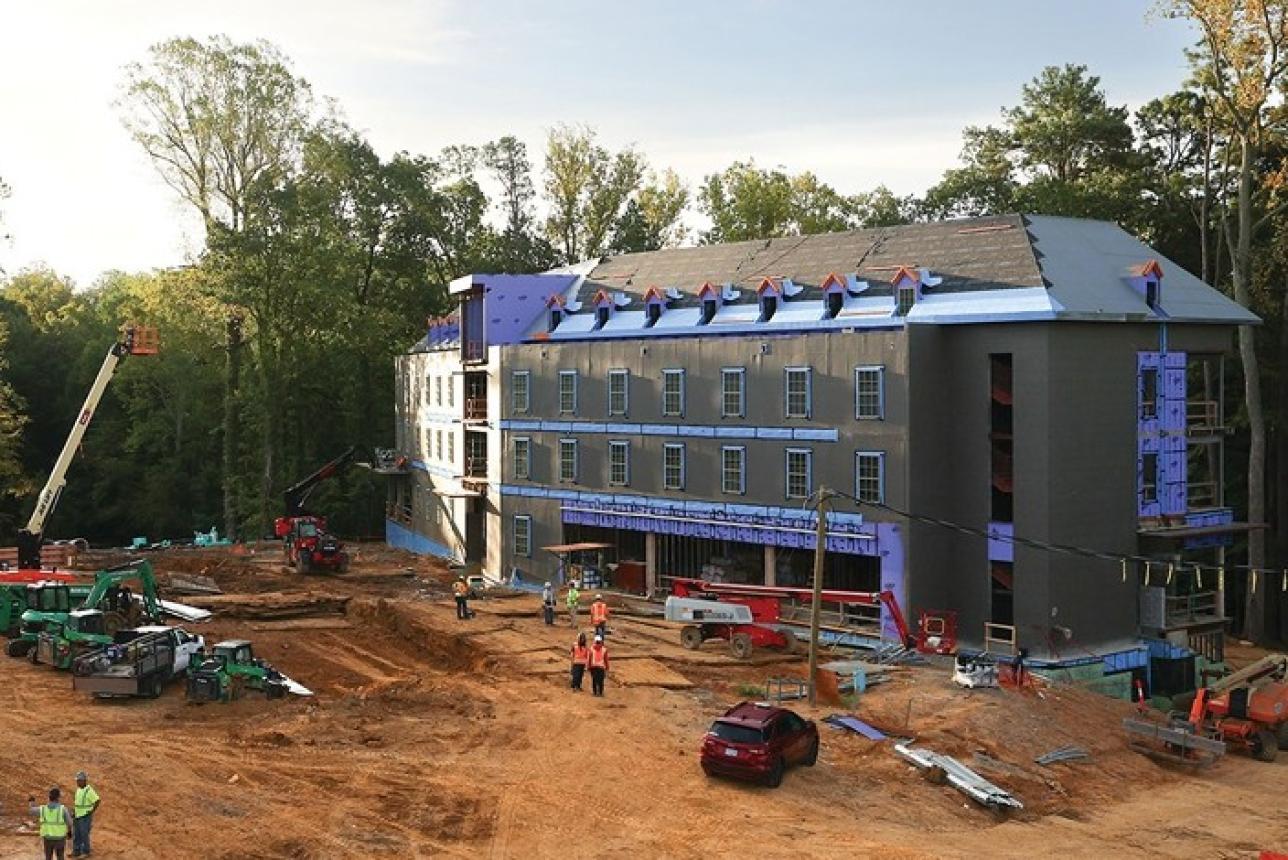 A group of construction workers completing exterior renovations on a building on campus.