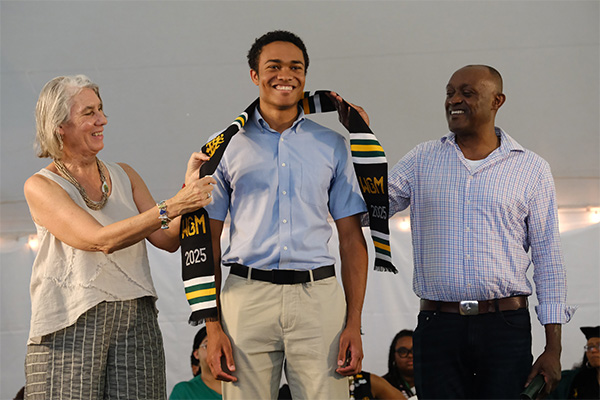 Family members bestow a stole on a graduate during the Donning of the Kente ceremony.