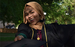 A student poses for a portrait in regalia.