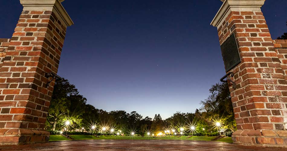 Brick entrance to the Sunken Garden with dusk night sky and lights in the distance
