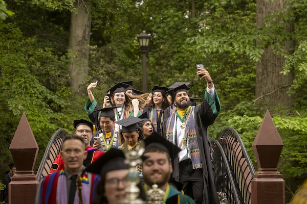 Members of the Class of 2025 take selfies as they cross the Crim Dell bridge