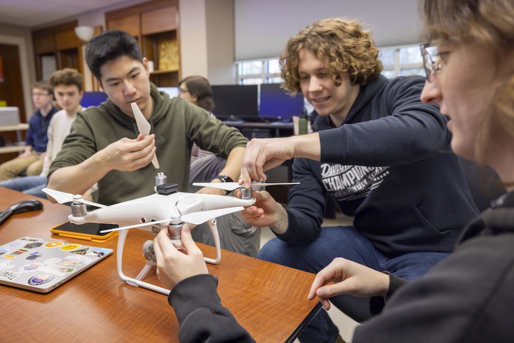 Three students work on assembling a drone