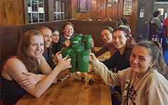 A group of students seated at the Green Leafe toasting with large green mugs