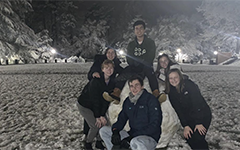 Five students building a snow sculpture in the Sunken Garden at night
