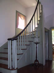 A spiral staircase with concave paneling rises from the 28-foot long central passage.