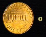 Tiny glass trade bead (modern penny shown for scale).